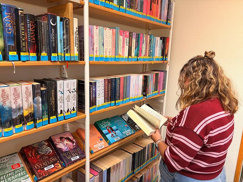 Lesen in der Stadtbücherei Coburg Eine junge Frau liest vor einem Bücherregal in der Stadtbücherei Coburg.