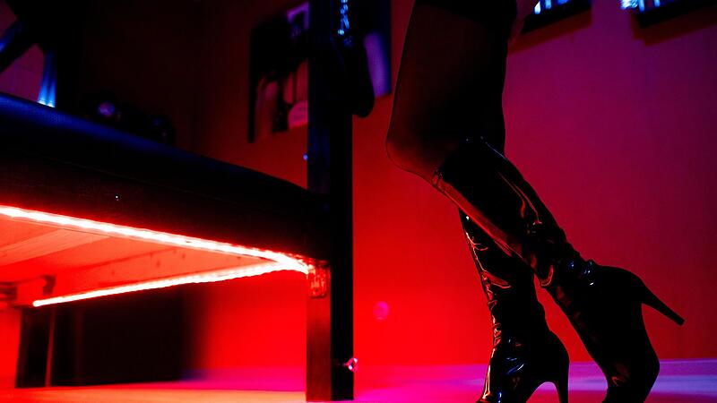 Eine Prostituierte steht an einem rot beleuchteten Bett in einem Studio. Die Union will den Kauf von Sex verbieten und das aktuell geltende Prostitutionsgesetz kippen.