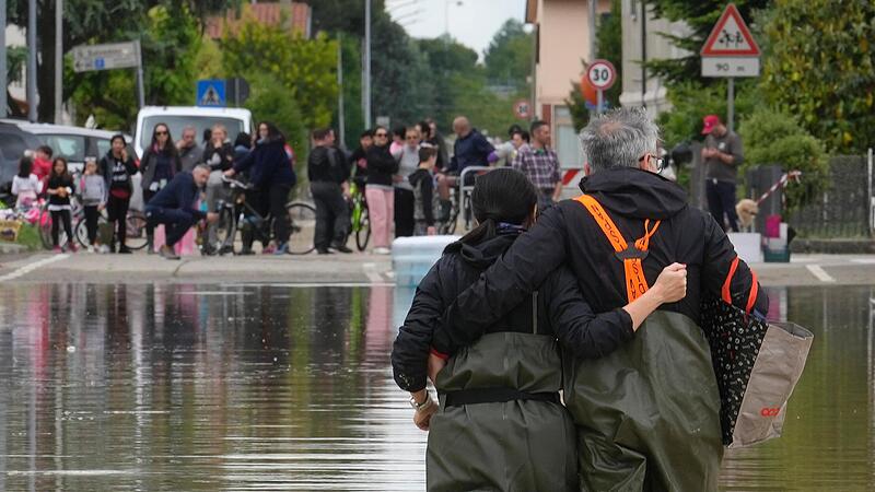 Ein Paar geht auf einer überfluteten Straße in Lugo. Nach den Unwettern und Überschwemmungen in Italien ist die Anzahl der Opfer weiter gestiegen.
