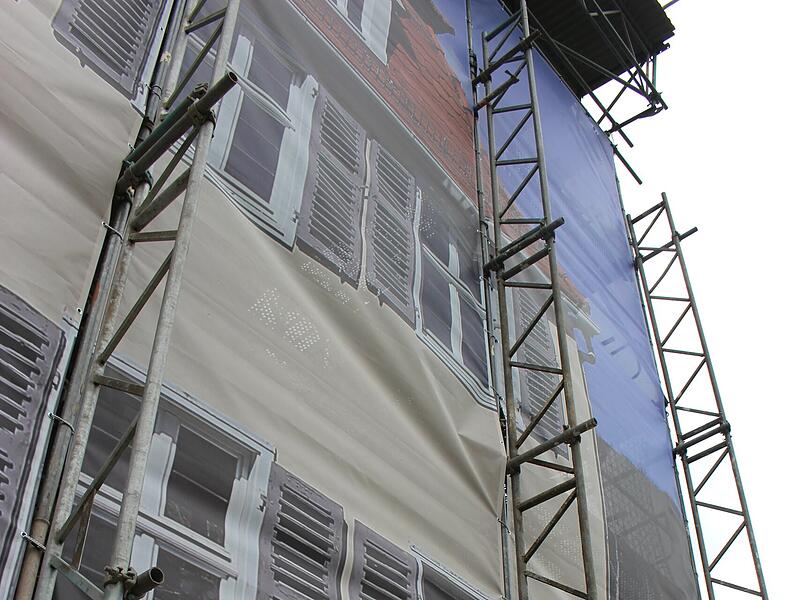 Foto aus dem Jahr 2025: Die Arbeiter wandeln versteckt hinter einem Fotovorhang des Geb&auml;udes.