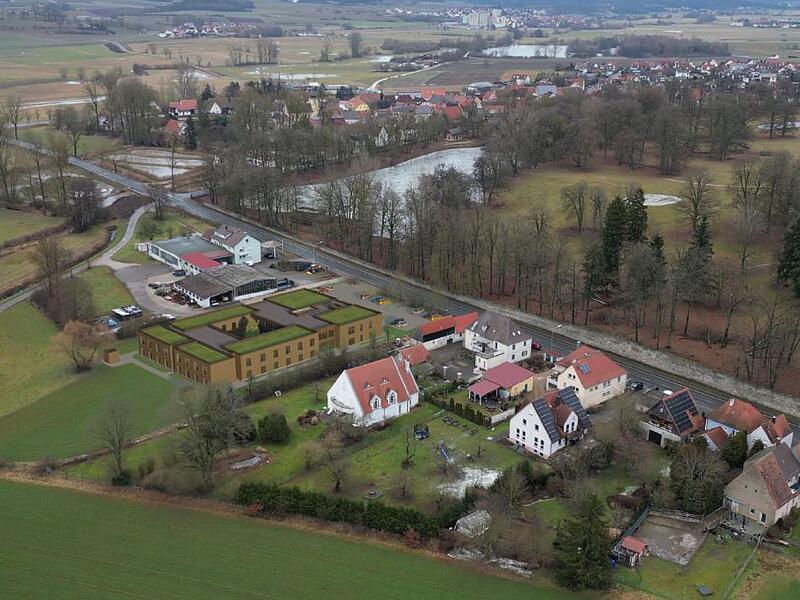 Seniorenheim Pommersfelden Visualisierung aus der Präsentation. Deutlich zu erkennen in der Bildmitte der Gebäudekomplex mit begrüntem Dach an der Ortsdurchfahrt.