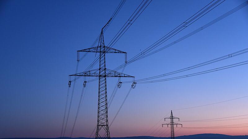Strommasten in der Morgendämmerung auf einem Feld Strommasten in der Morgendämmerung auf einem Feld