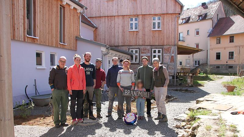 Auf dem Foto von links stehen vor den Wohnh&auml;usern und der M&uuml;hle: Klaus Reichert, Anna Baumgartner, Simon Memmel, Rainer Neubauer, Andr&eacute; und Magdalena Gl&ouml;ckner, Jakob mit Kind sowie Martina Neubauer.