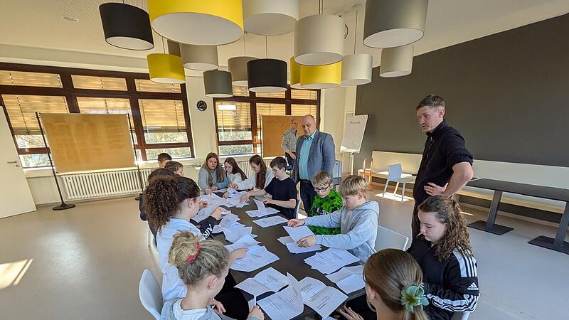 B&uuml;rgermeister Daniel Wehner und Jugendpfleger Christian Wagner beobachten, wie Sch&uuml;lerinnen und Sch&uuml;ler der Mittelschule Burkardroth die Stimmzettel der U-18 Wahl z&auml;hlen und sortieren.