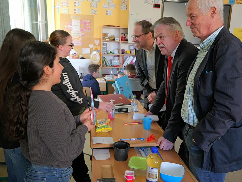 CvL-Realschulleiter Dr. Matthias Niedermeier (hinten), Landrat Klaus Peter S&ouml;llner (mitte), Dr. Michael Pfitzner (vorn) lassen sich von Sch&uuml;lerinnen die nachhaltige Nutzung von Rohstoffen und Produkten erl&auml;utern.