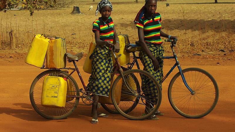 Eine typische Szene aus Burkina Faso in Afrika: Zwei Mädchen beim Wasserholen mit Kanistern. Eine typische Szene aus Burkina Faso in Afrika: Zwei Mädchen beim Wasserholen mit Kanistern.