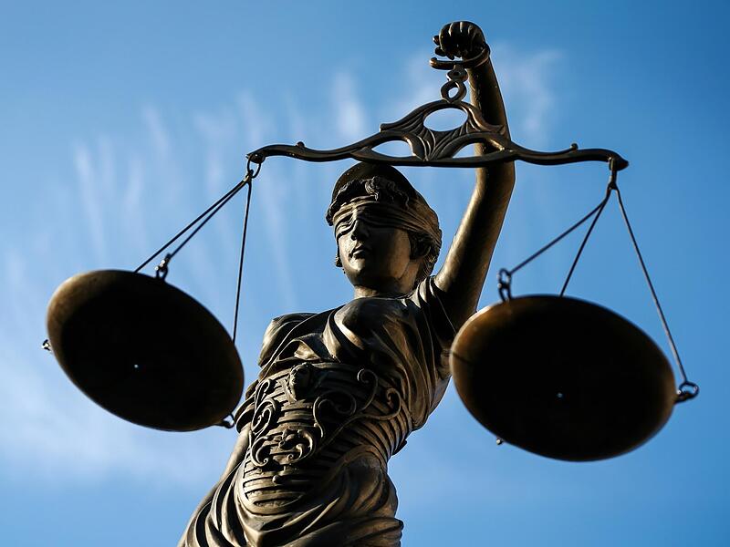 Eine Statue der Justitia hält eine Waage in ihrer Hand.