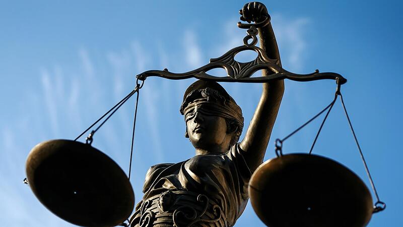 Eine Statue der Justitia hält eine Waage in ihrer Hand.