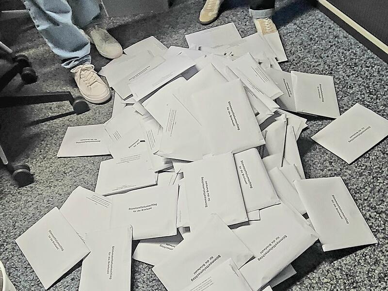 Wirtschaftsf&ouml;rderer Sebastian B&uuml;nner und Stadtwerke-Gesch&auml;ftsf&uuml;hrerin Anja Binder leeren eine Wahlurne im Rathaus Bad Kissingen aus.