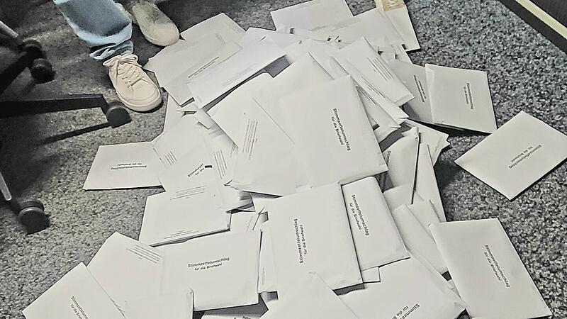 Wirtschaftsf&ouml;rderer Sebastian B&uuml;nner und Stadtwerke-Gesch&auml;ftsf&uuml;hrerin Anja Binder leeren eine Wahlurne im Rathaus Bad Kissingen aus.