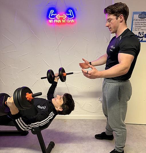 Fitnesstrainer Moritz vom Kulmbacher Fitnessstudio Fit &rsquo;n Fun leitet einen Probanden fachkundig an.