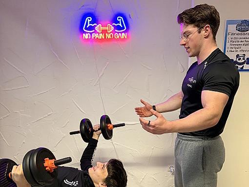 Fitnesstrainer Moritz vom Kulmbacher Fitnessstudio Fit &rsquo;n Fun leitet einen Probanden fachkundig an.
