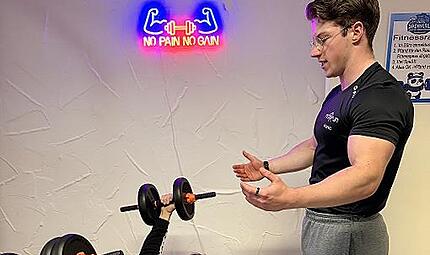 Fitnesstrainer Moritz vom Kulmbacher Fitnessstudio Fit &rsquo;n Fun leitet einen Probanden fachkundig an.