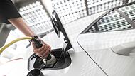 Frau steckt einen Ladestecker für ein E-Auto in eine Buchse Frau steckt einen Ladestecker für ein E-Auto in eine Buchse
