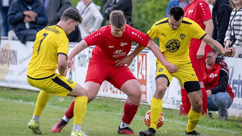 Die Merkendorfer Jan Pfister (links) und Ionut Ojica (rechts)  nehmen den G&auml;stespieler  Julian Martin in  die Zange.