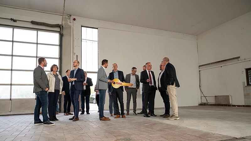 Die G&auml;ste schauen sich in der noch leeren Halle um, in der Mitte mit Schl&uuml;ssel der Pr&auml;sident der Hochschule Coburg, Stefan Gast.