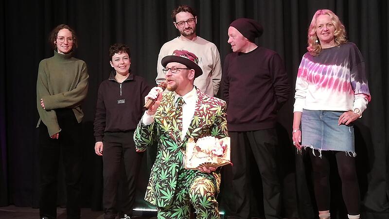 Moderator Michael Jakob (kniend) bei der Preisverleihung in der Kulturfabrik Fortuna in H&ouml;chstadt mit (v. l.) Lotta Emilia, Leonie Weindl, Samson, Wehwalt Koslovsky, Sonja Hingman