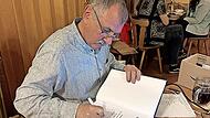 Autor G&uuml;nter B&ouml;hner schrieb pers&ouml;nliche Widmungen in die B&uuml;cher, die er am Vortragsabend verkaufte.