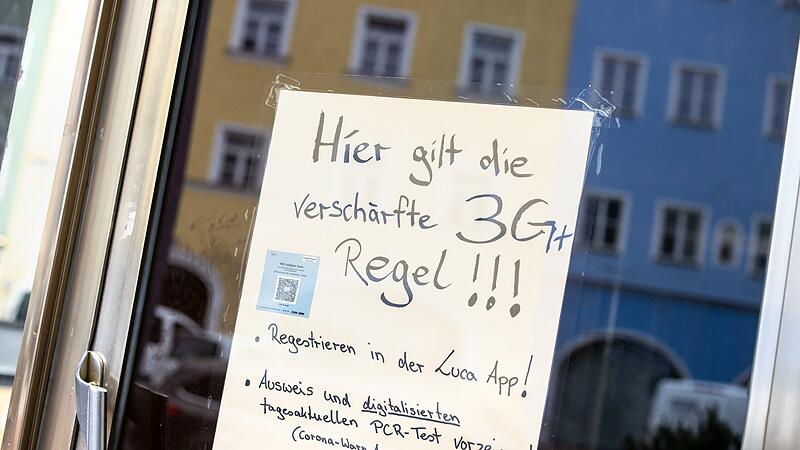 Auf einem Zettel an einer Scheibe von einem Café wird auf die Anwendung der verschärften „3G+ Regeln“.