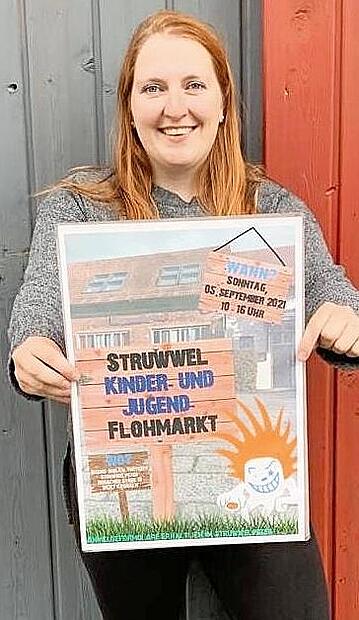 Alexandra Rehm trägt das Plakat zum Kinder- und Jugendflohmarkt am 5. September.