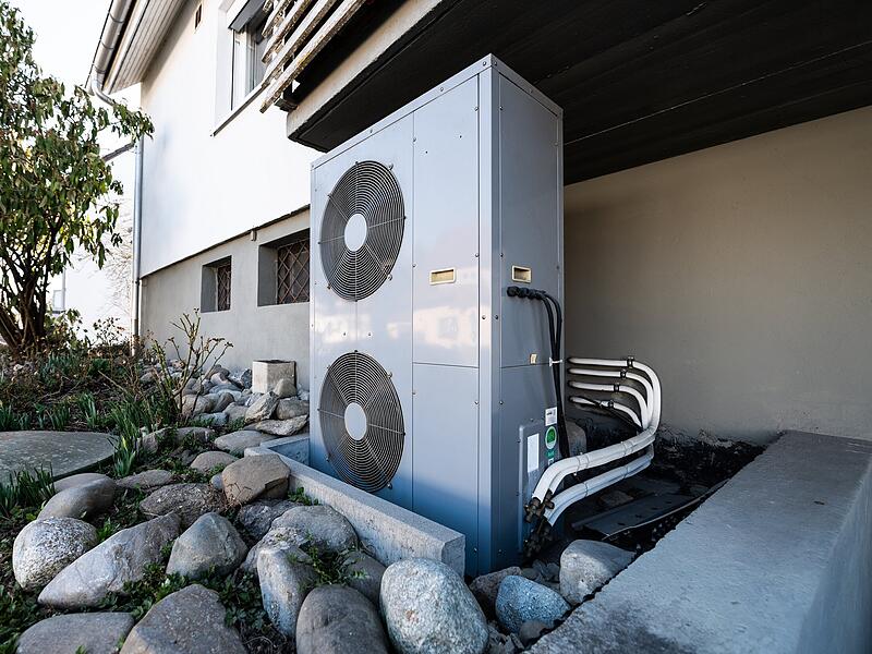 Die Lüftungsanlage einer Wärmepumpe steht vor einem Wohnhaus. Die Lüftungsanlage einer Wärmepumpe steht vor einem Wohnhaus.