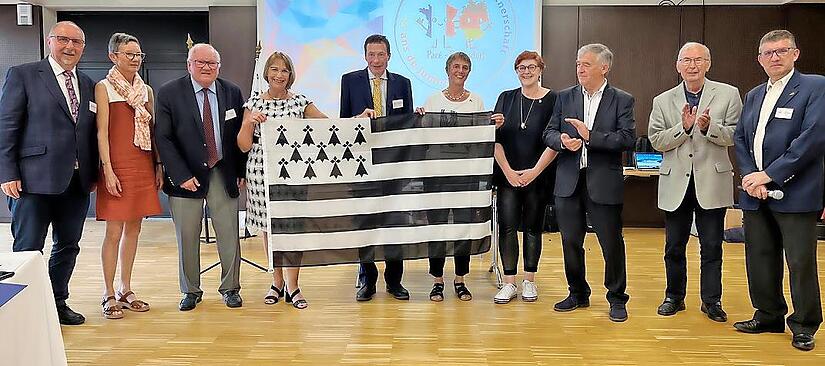 Der Baiersdorfer Partnerschaftsverein „Le Pont pour Pacé“ bekam eine bretonische Fahne zum Jubiläum geschenkt (v. l.): Andreas Galster (Altbürgermeister Baiersdorf), Gaëlle Guérin (Kulturbeauftragte Pacé) Paul Kerdraon (Altbürgermeister Pacé), Eli...