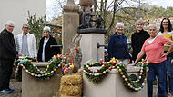 Die Frauen vom Heimat- und Wanderverein Aschach stehen vor dem geschmückten Osterbrunnen