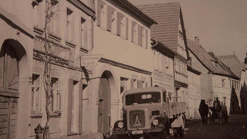 Dieses Bild wurde zwischen 1945 und 1949 in der „Ritter-von-Schmitt-Straße“ aufgenommen, wo sich ein parkender Lastwagen und ein Pferdegespann die Straße teilen. Dieses Bild wurde zwischen 1945 und 1949 in der „Ritter-von-Schmitt-Straße“ aufgenommen, wo sich ein parkender Lastwagen und ein Pferdegespann die Straße teilen.