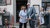 Oberbürgermeister Dirk Vogel zerschneidet mit Marika Hoffmann das rote Band zum neuen Restaurant.