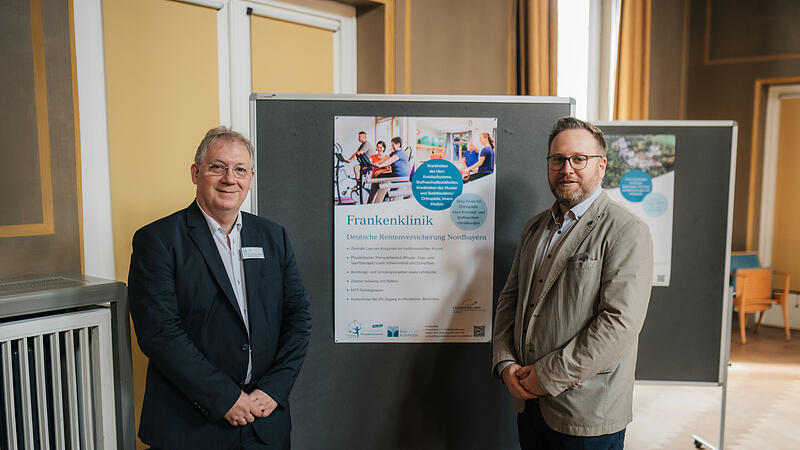 Von der Frankenklinik DRV Nordbayern: Chefarzt Dr. med. Christian Kuzman-Anton (l.) und Moritz Kaiser, Stellvertretender Kaufm&auml;nnischer Leiter vor dem Poster der Frankenklinik