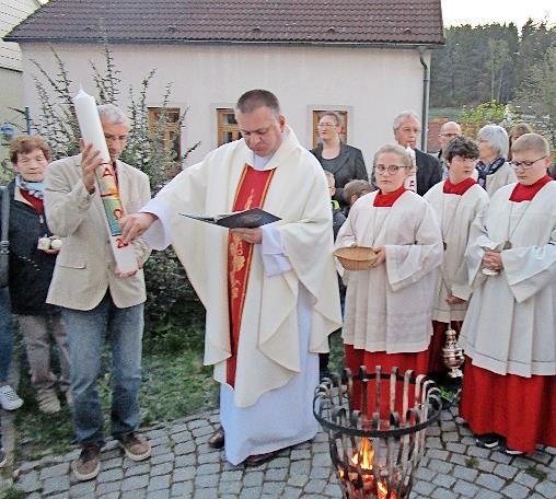 Pfarrer Michal Osak festigt Symbole auf die Osterkerze. Pfarrer Michal Osak festigt Symbole auf die Osterkerze.