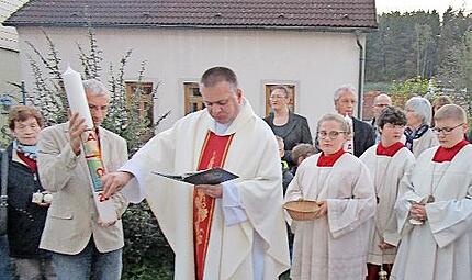 Pfarrer Michal Osak festigt Symbole auf die Osterkerze.