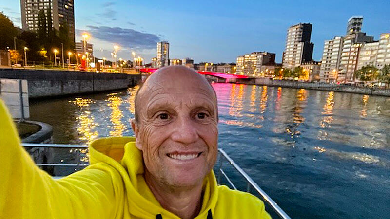 Siegfried Reitberger auf seinem Hausboot vor der Kulisse der belgischen Stadt L&uuml;ttich