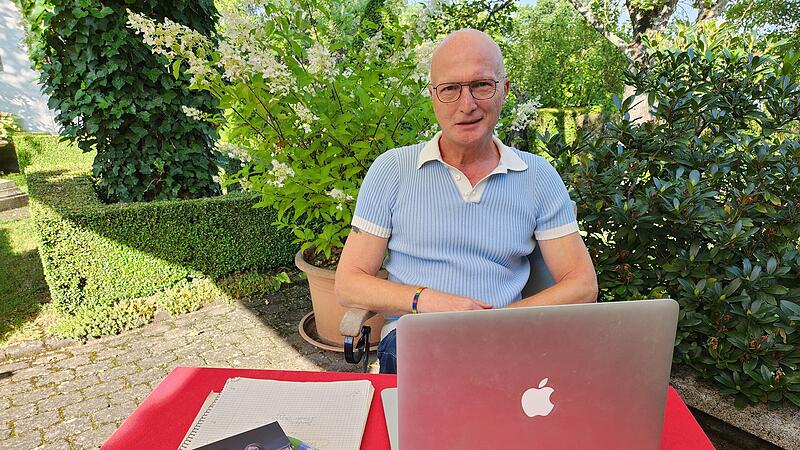 Hubert Ziegler alias Orlando Stein in seinem Garten, wo er am Laptop schreibt. Vor ihm sein Deb&uuml;t-Roman: "Bulle und Finn".