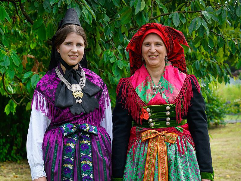 Das Buch &bdquo;Evangelische Trachten in der Fr&auml;nkischen Schweiz&ldquo; zeigt zwei Trachten aus der Region: Links eine typisch evangelische schwarz-lila Tracht, rechts eine farbenfrohe katholische Tracht &ndash; ein Gegensatz, der lange als typisch galt.