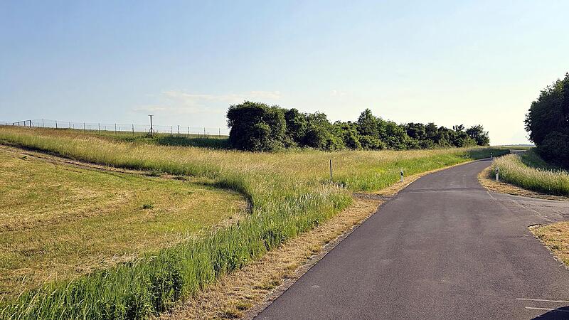 Von rechts, aus Richtung des Baches Weisach kommend, wird die Weisach und dann diese Straße (hier Blick Richtung Kraisdorf) unterbohrt und das Stromkabel um die Umzäunung des Brunnens 2 (oben links) verlegt.