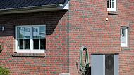 Eine Luft-Wasser-W&auml;rmepumpe steht vor einem Haus