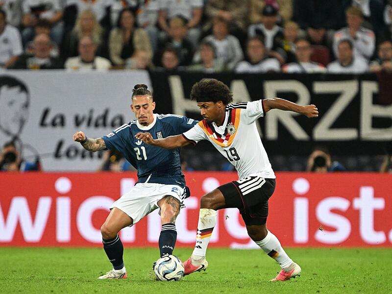Vorne im Duell Karim Adeyemi im Duell mit einem Griechen, hinten Frankens "Loddar" mit dem WM-Pokal. Vorne im Duell Karim Adeyemi im Duell mit einem Griechen, hinten Frankens "Loddar" mit dem WM-Pokal.