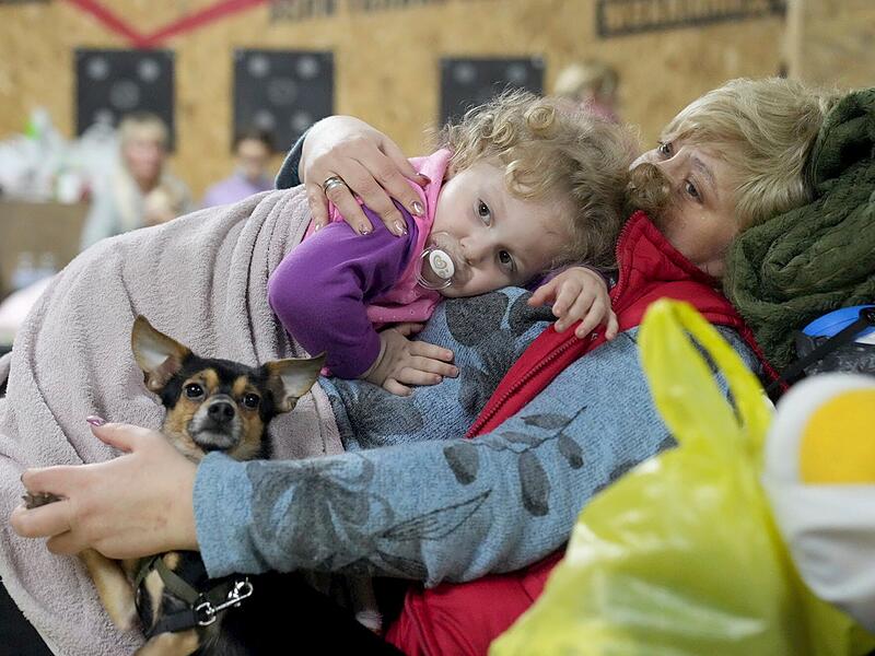 Eine Frau hält ein Kind und einen Hund in einem Unterstand in einem Gebäude im umkämpften Mariupol. In der zweitgrößten Stadt der Ukraine sind Straßenkämpfe ausgebrochen und russische Truppen haben strategische Häfen im Süden des Landes besetzt.