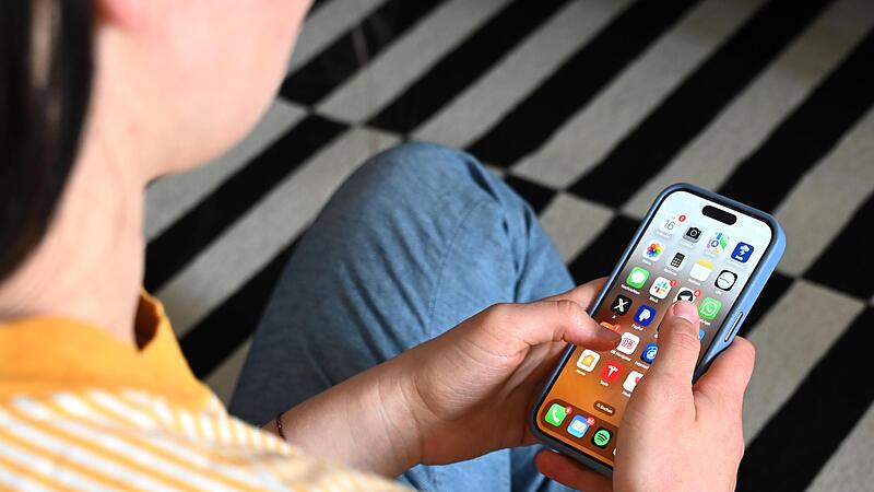 Eine Jugendliche blickt auf das Display ihres Smartphones, auf dem verschiedene Apps zu sehen sind.