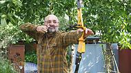 Jürgen Matschl demonstriert im heimischen Garten, wie der Bogen gespannt werden muss.