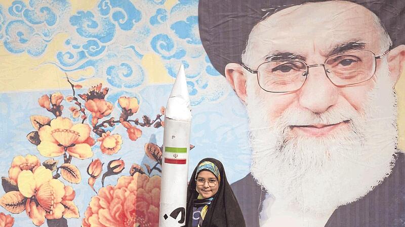 Ein iranisches Schulmädchen steht mit dem Modell einer Rakete vor einem Porträt von Religionsführer Ali Chamenei in Teheran. &#160;&#160;