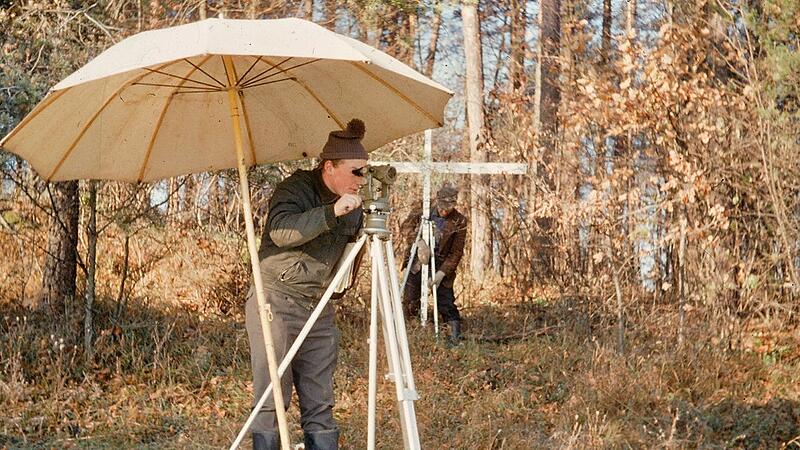 Vermessen, Zeichnen und Planen geh&ouml;ren zum Kerngesch&auml;ft des fr&uuml;heren Flurbereinigungsamts. Die Szene aus dem Jahr 1967 zeigt einen Mitarbeiter in Engelhardsberg (Landkreis Forchheim) am Theodolit, einem Winkelmessger&auml;t. Im Hintergrund die sogenannte Basislatte.
