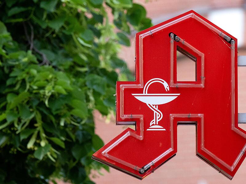 Das Logo einer Apotheke hängt an einem Gebäude in  Bayern.
