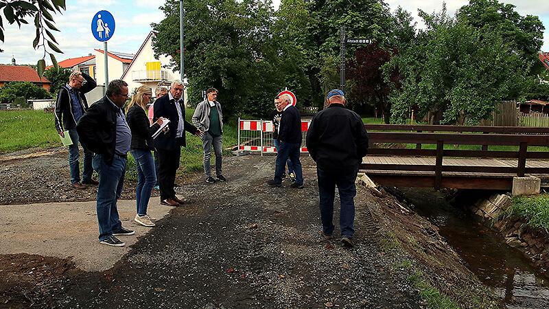 An dieser Stelle auf H&ouml;he der Eiswiese an der Br&uuml;cke zum &Uuml;bergang in die Innenstadt war der Weg gut 50 Zentimeter tief weggesp&uuml;lt. B&uuml;rgermeister J&uuml;rgen Hennemann (F&uuml;nfter von links) erl&auml;uterte die Sachlage und wie der Schaden ausgebessert wurde.