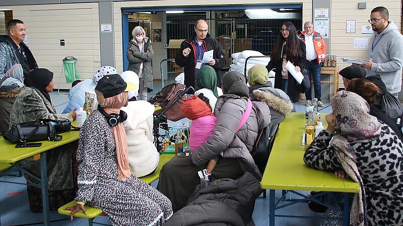 Frank Gerstner (stehend, Dritter von links), der Leiter der Sozialen Dienste beim Roten Kreuz, hei&szlig;t die 20 Asylbewerber in der Lichtenfelser Berufsschulturnhalle willkommen. Anschlie&szlig;end werden den Afghanen und Somaliern familienweise die proviso...