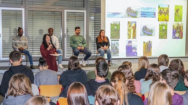 Podiumsdiskussion an der Dr.-Ernst-Schmidt-Realschule Ebern (von rechts): Nahida aus Syrien, Tufan aus Afghanistan, Seba und André, Elfenbeinküste, am Mikrofon Heidi Hauguth.