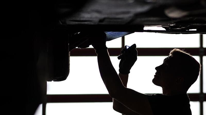 Ein Mechaniker begutachtet ein Auto in einer Werkstatt Ein Mechaniker begutachtet ein Auto in einer Werkstatt
