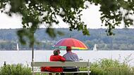 Renter sitzen mit einem Schirm am See
