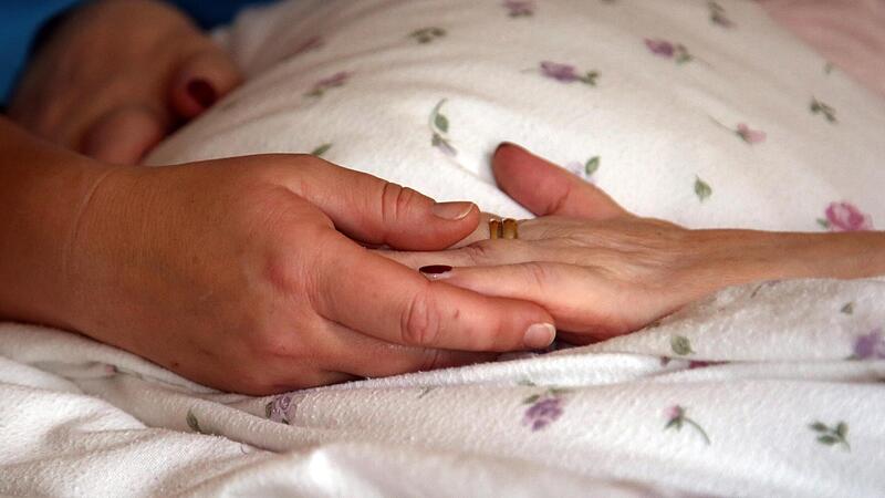 Die Hände einer Bewohnerin liegen in einem Hospiz auf einer Bettdecke. Die Hände einer Bewohnerin liegen in einem Hospiz auf einer Bettdecke.